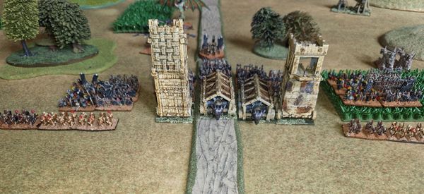 Undead forces with siege towers advancing on the castle gatehouse flanked by Tomb King infantry