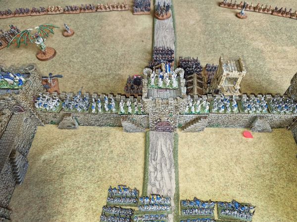 Aerial view of the castle walls with Elven defenders holding the battlements against the undead assault and a fell beast circling
