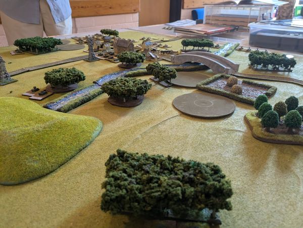 Battlefield overview showing tanks, wooded areas and a bridge with a river crossing