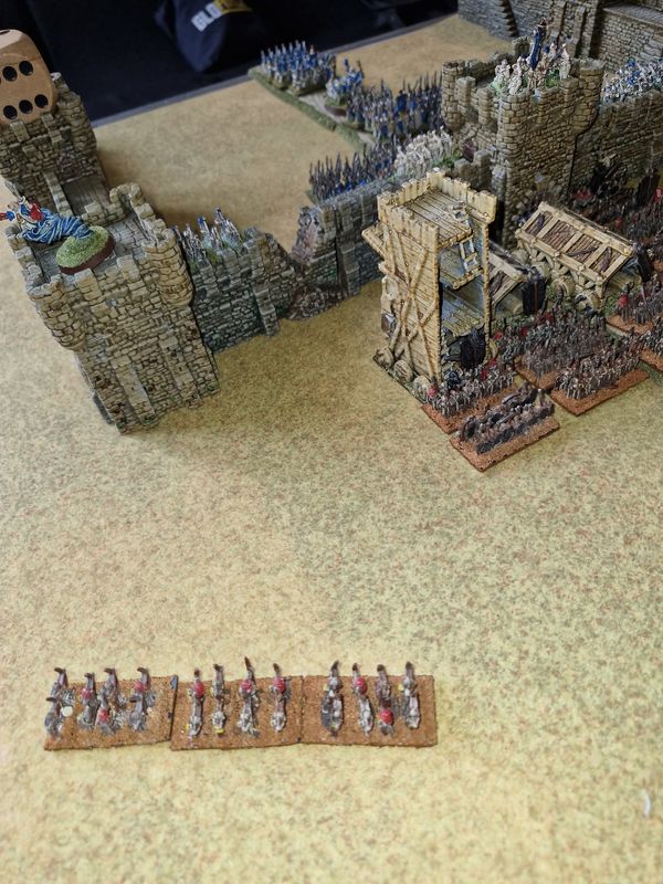 Undead forces with siege tower at the castle walls while Elven spearmen man the battlements and a unit approaches below